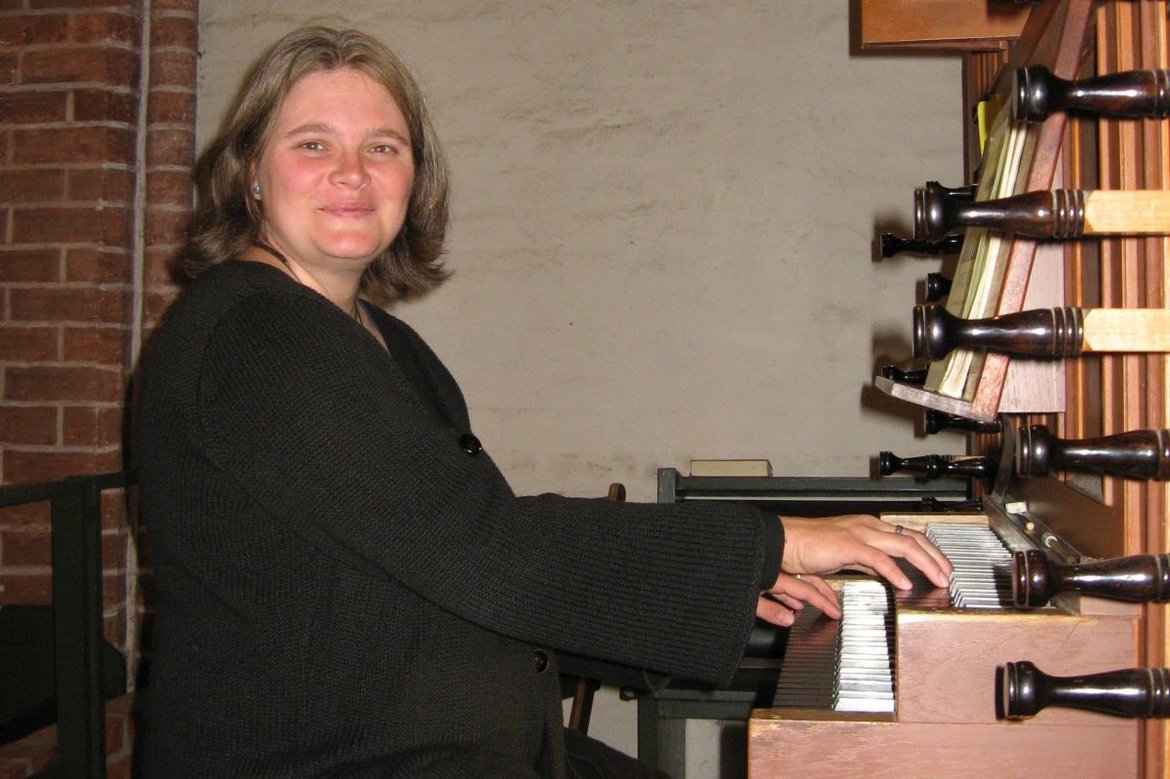 Friederike Raupers ist schwarz gekleidet, sitzt an der Orgel und lächelt freundlich.