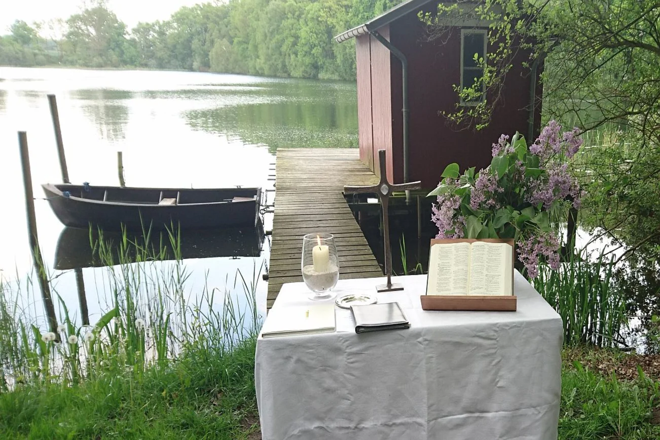 Altar am See mit Bibel, im Hintergrund ein Ruderboot