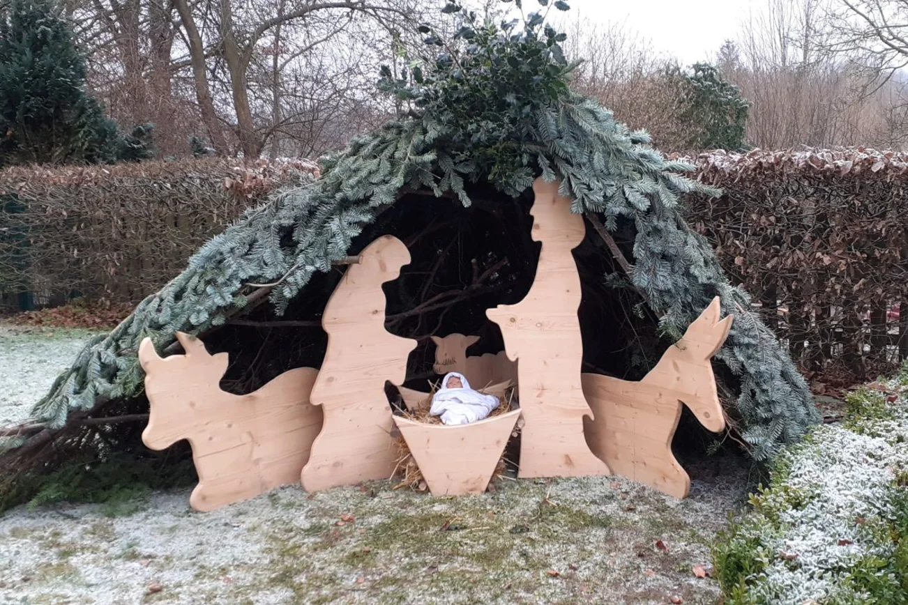 Maria und Josef mit den Tieren und dem Kind in den Windeln aus Holz gearbeitet auf dem Rasen stehend.