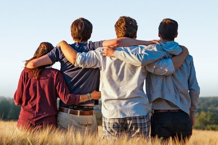 Vier junge Menschen stehen mit dem Rücken zum Betrachter in einem Getreidefeld - Copyright: Pastorin Judith Fincke