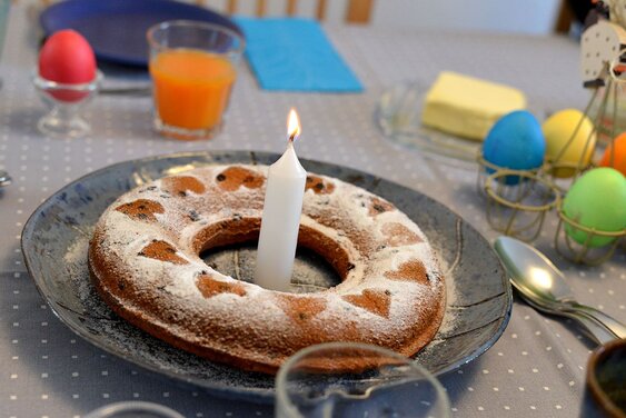 Bunter Eier und runder Kuchen mit Kerze - Copyright: Foto:Lotz