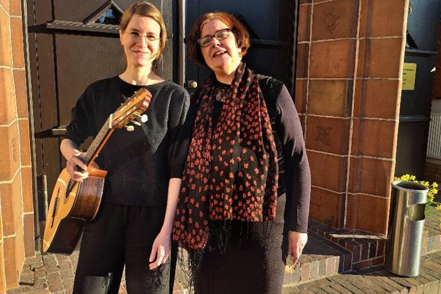 Zwei Frauen stehen vor einem großen Tor und eine Frau trägt eine Gitarre - Copyright: Sabine Loredo Silva