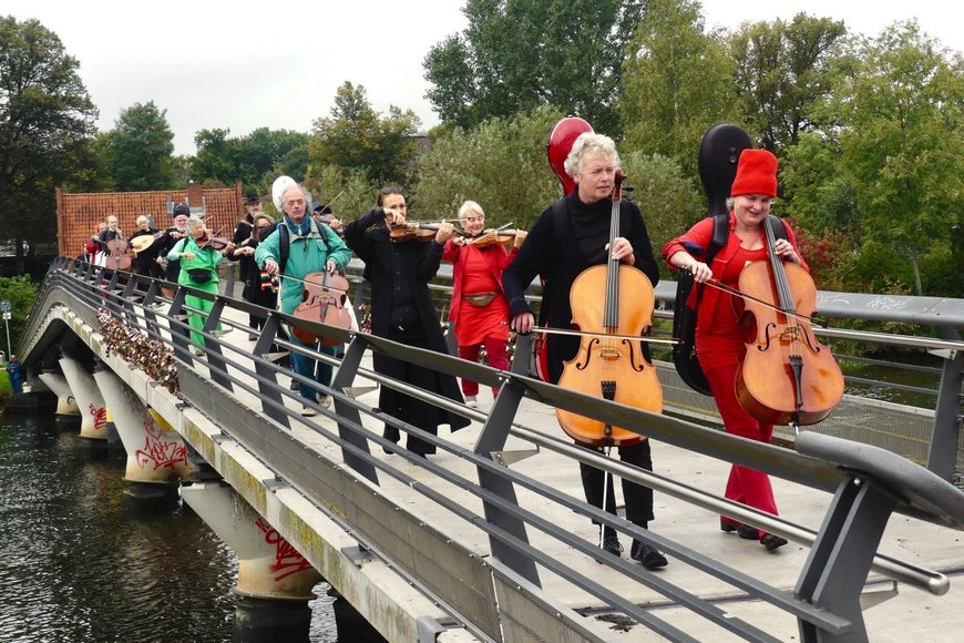 Musizierende überqueren eine Brücke mit Streichinstrumenten - Copyright: Cornelius Heinze