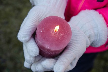 Zwei Hände in weißen Handschuhen tragen eine brennende, rosa Kerze - Copyright: N. Schwarz © GemeindebriefDruckerei.de