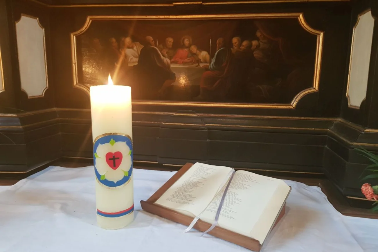 Entzündete Kerze mit Lutherrose auf dem Altar 
