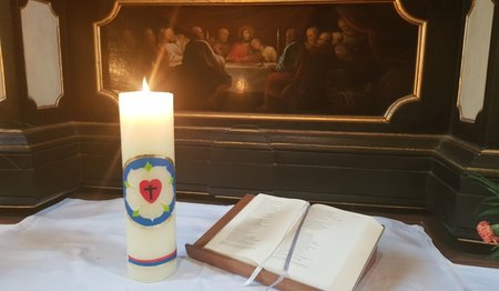 Entzündete Kerze mit Lutherrose auf dem Altar 