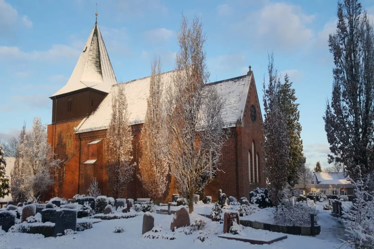 Vor dem blauen Himmel sieht man die schneebedeckte St. Johanniskirche zu Krummesse.Schneebedeckt