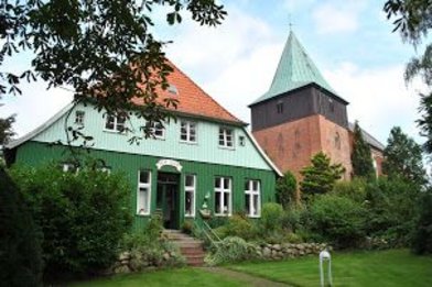 Fasade vom Pastorat in Krummesse mit dem Kirchturm im Hintergrund - Copyright: Pn. Friederike Schwetasch