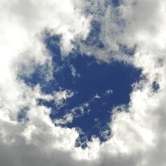 Ein Kreis blauer Himmel leuchtet durch eine Wolkendecke