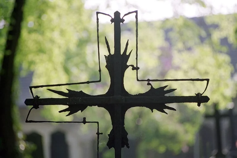 Schwarzes, verwittertes Kreuz von grünem Hintergrund
