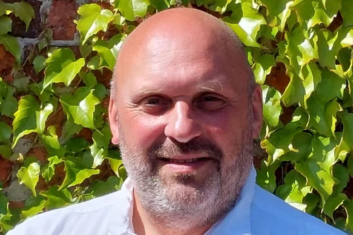 Pastor Sven Rehbein vor einer Mauer mit grünen Weinblättern